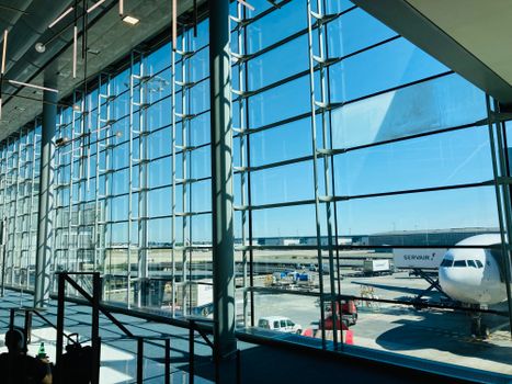 Spacious airport terminal with glass facade overlooking airplane on tarmac.