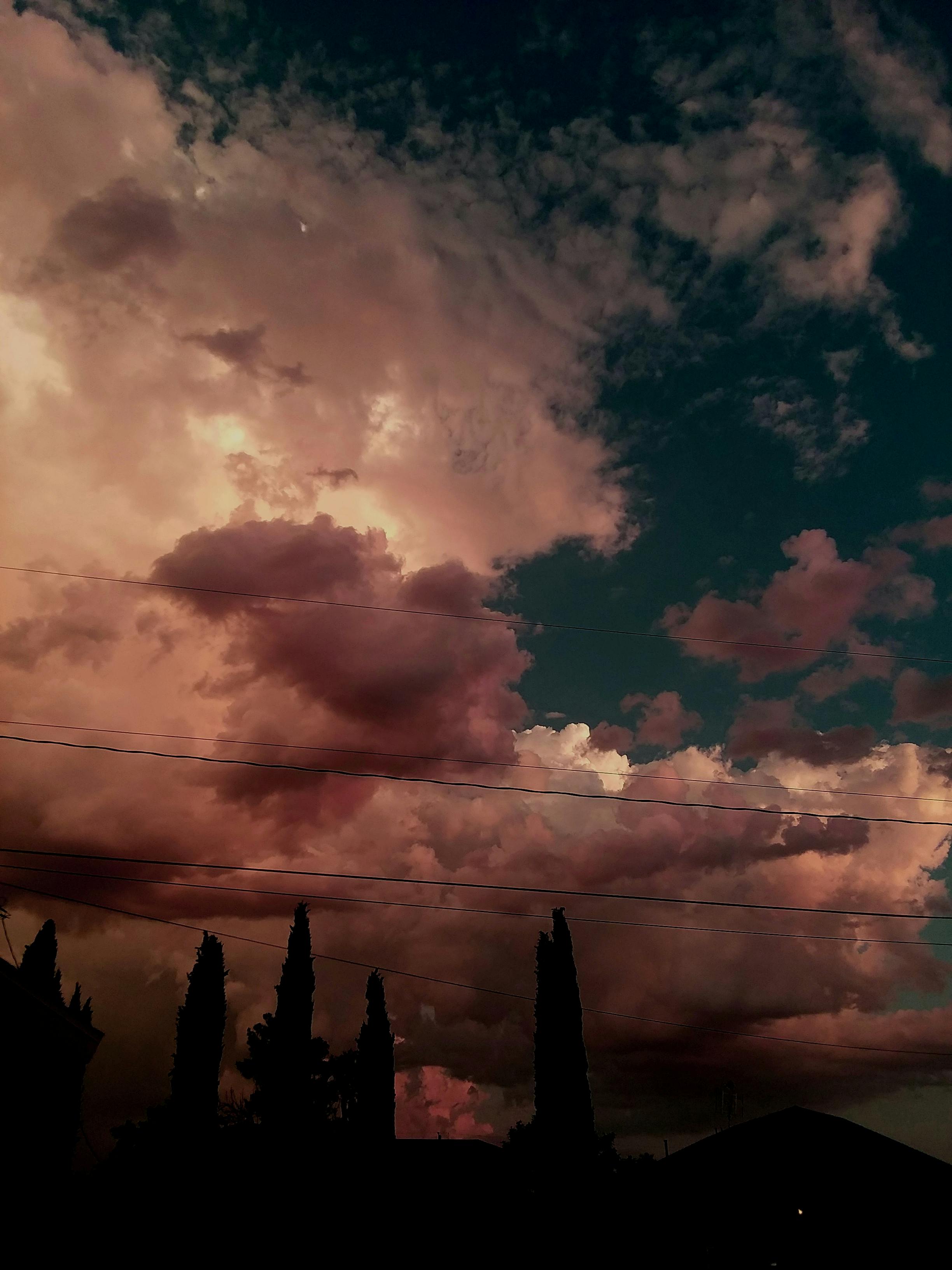 Stunning dramatic sunset clouds over Kingman, Arizona, featuring vibrant colors and silhouetted trees.