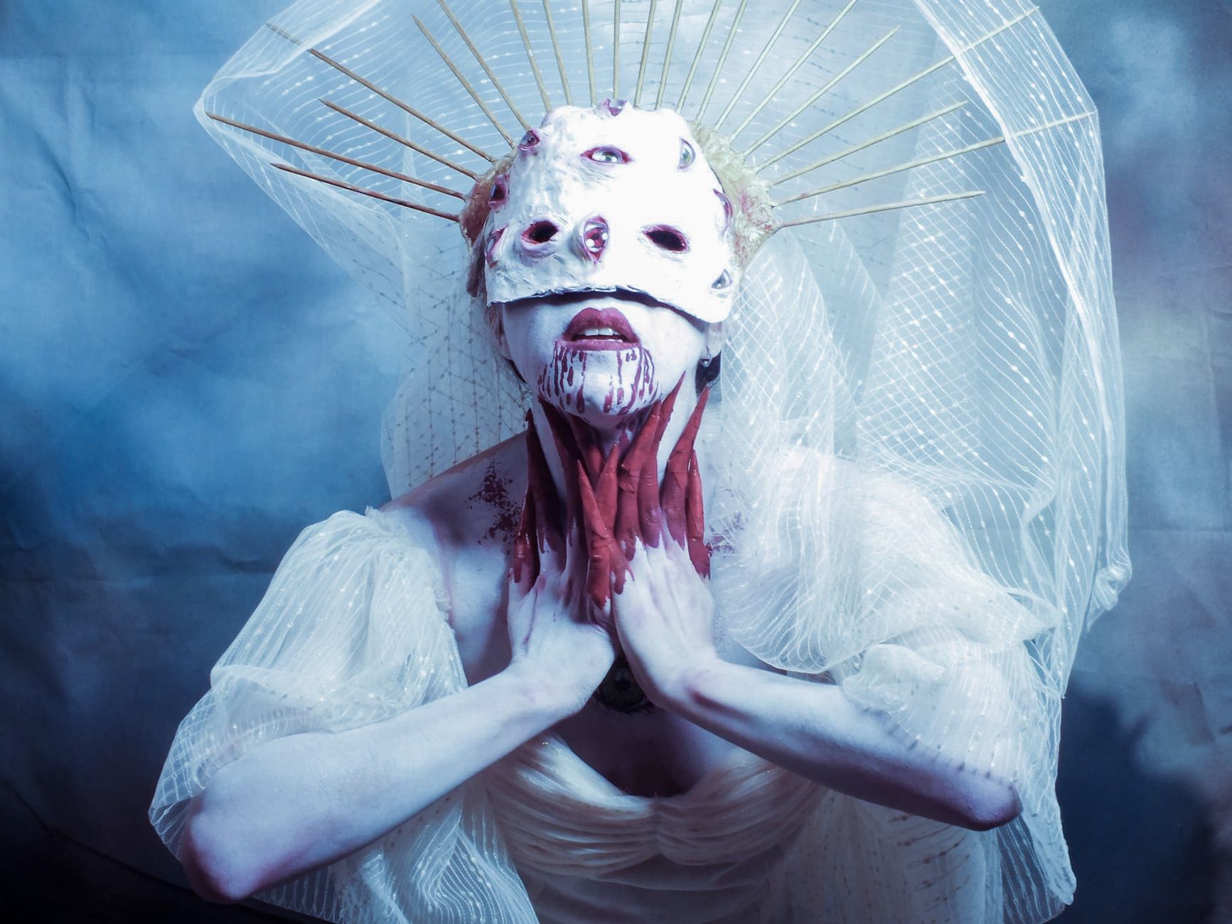 Surreal portrait of a gothic woman in a mask and veil with a dramatic expression.