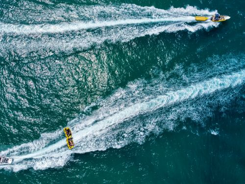 Free Aerial shot of two speedboats creating waves on the open sea on a bright day. Stock Photo