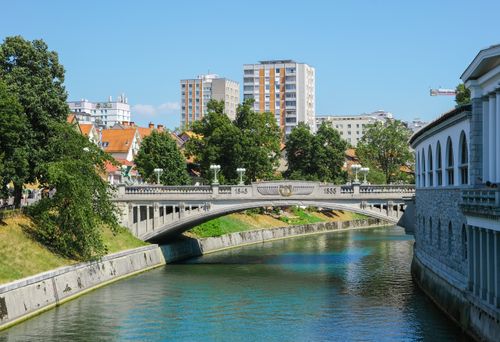 Free Picturesque urban landscape of Ljubljana with river, bridge, and residential buildings. Stock Photo