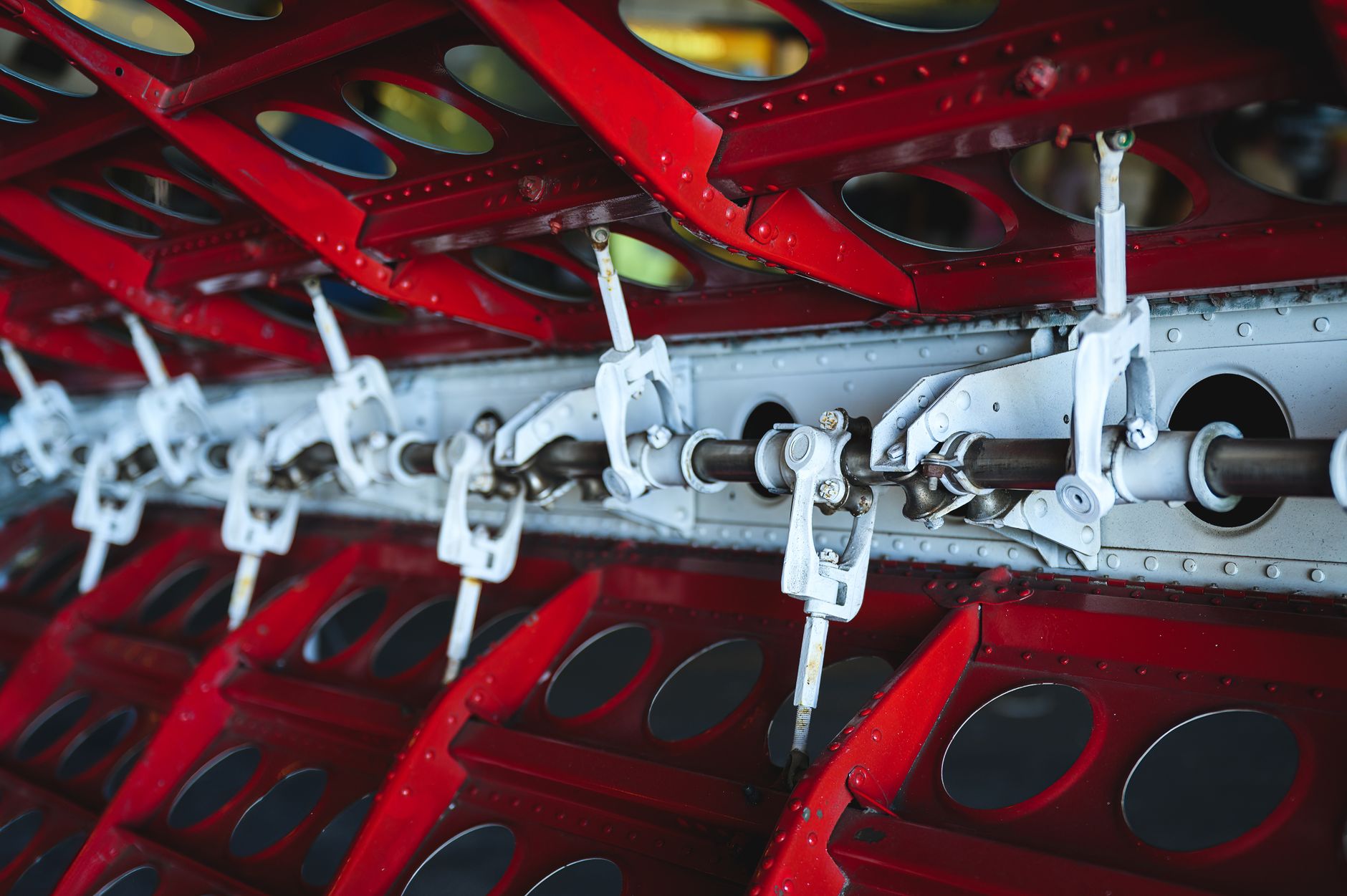 Close-up view of aircraft wing mechanism showcasing metal levers and vibrant colors.