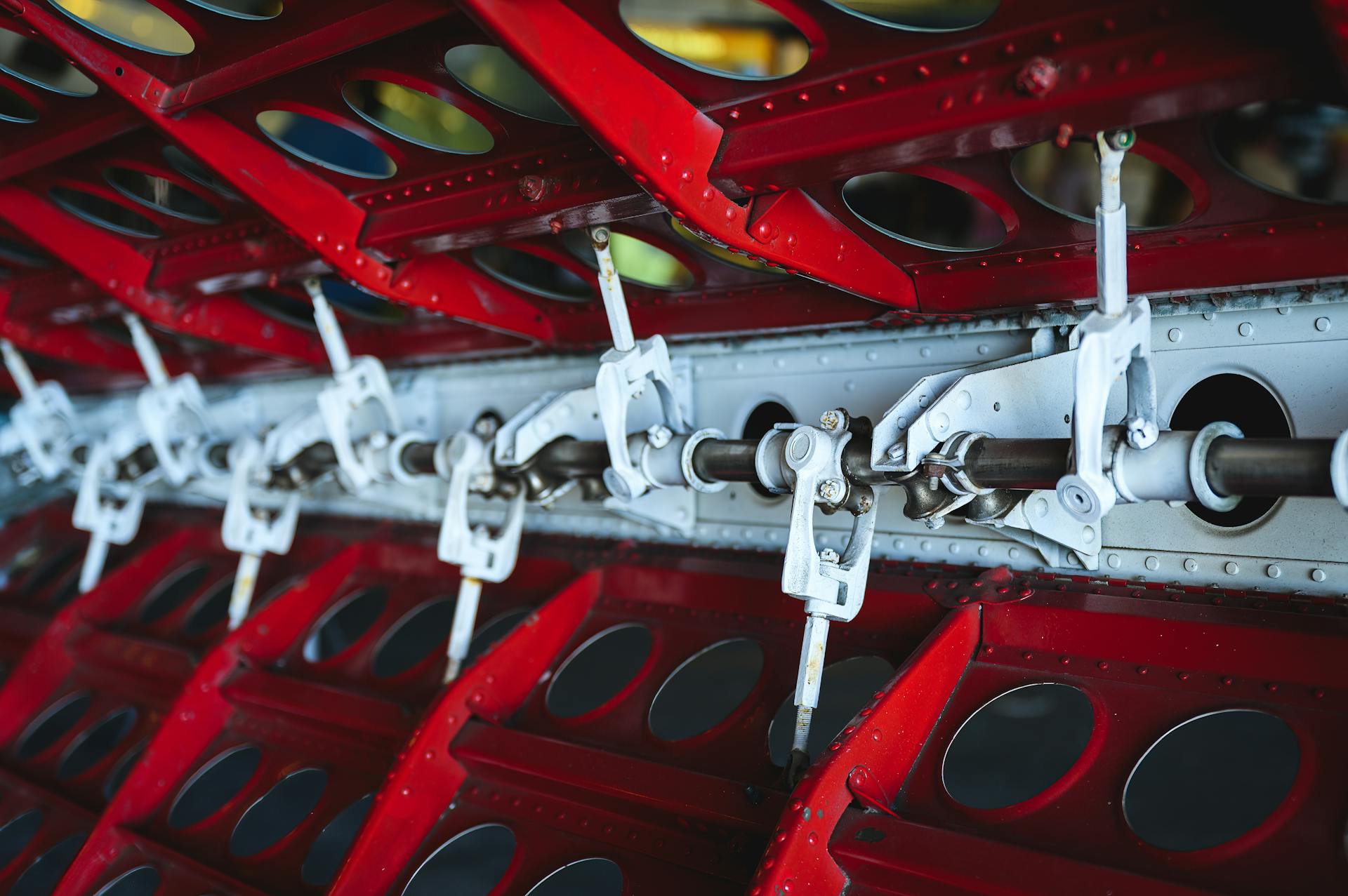 Close-up view of aircraft wing mechanism showcasing metal levers and vibrant colors.