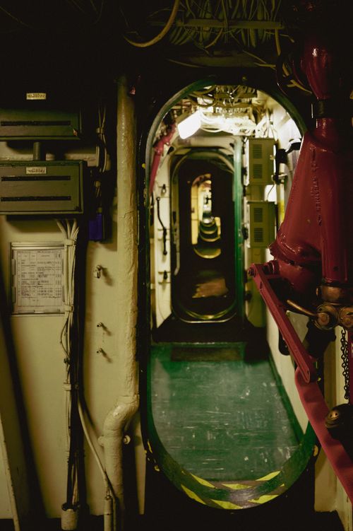 Free Dimly lit interior of a submarine showing a long corridor with visible equipment and wiring. Stock Photo