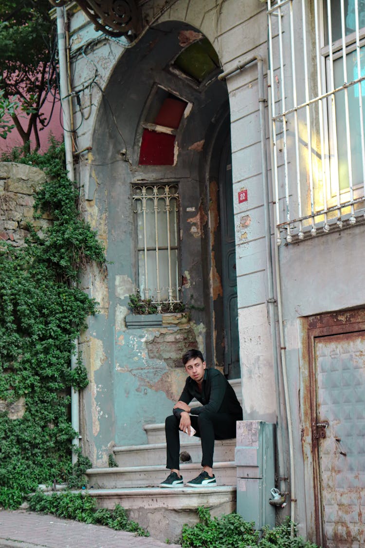 Man Sitting On Stairs Of Old Building