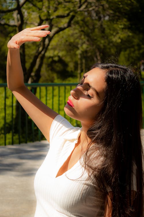 A Woman in White Shirt Covering Hand on her Face