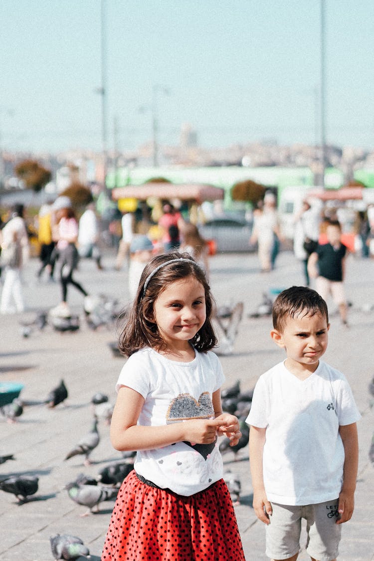 Brother And Sister Standing Beside Flock Of Pigeons