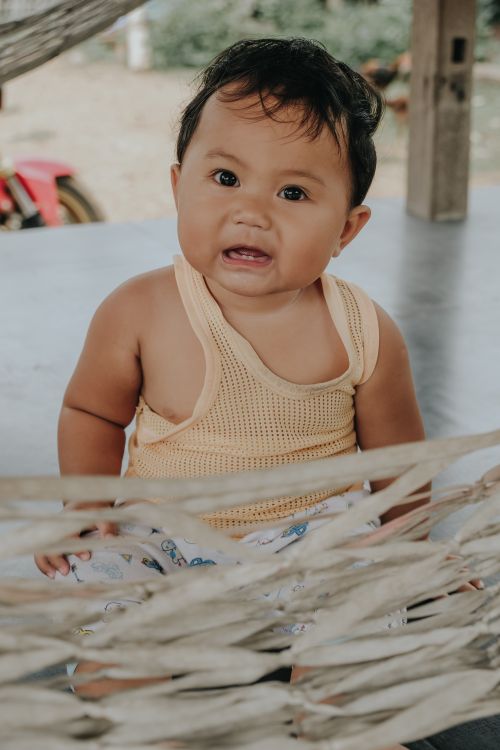 Free Charming baby in a yellow top sitting on a hammock outside, exuding cuteness and innocence. Stock Photo
