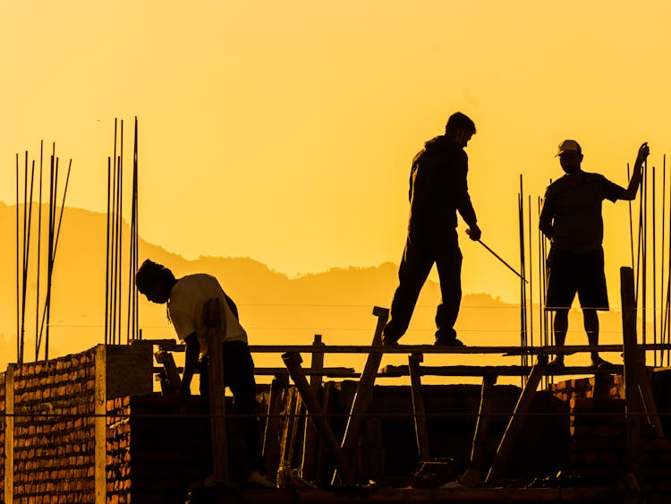 Silhouette Of Construction Workers At Sunset