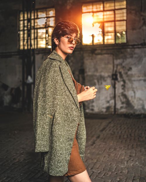 Free Trendy woman wearing sunglasses and a coat walking indoors with a cool vibe. Stock Photo
