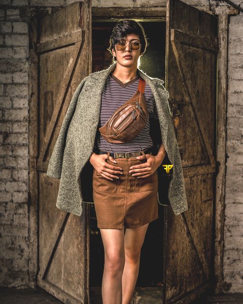 Free A stylish individual stands confidently in a rustic doorway with a vintage aesthetic. Stock Photo