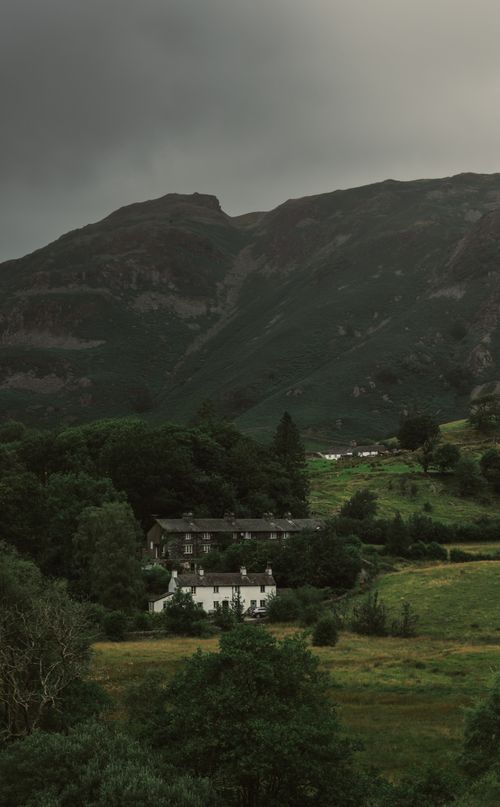 Free Scenic rural landscape featuring quaint cottages surrounded by lush green hills and valleys. Stock Photo