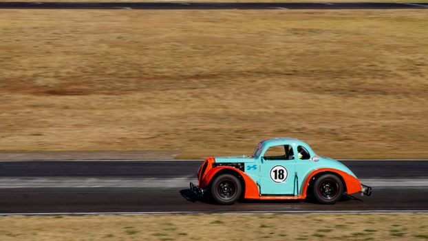 Classic racing car in motion on track showcasing speed and vintage design.