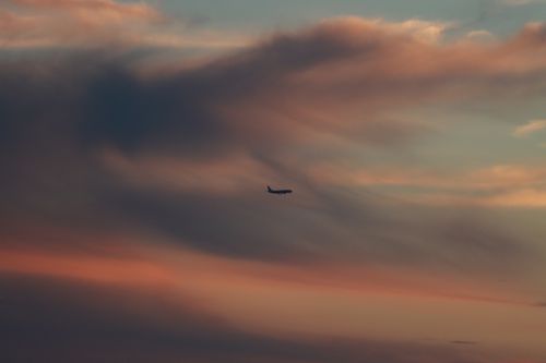 Free A solitary airplane flies against a dramatic sunset sky in Alghero, Sardinia. Stock Photo