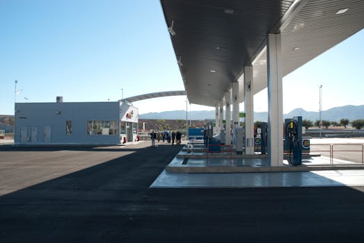 A modern gas station with a view of distant mountains, under a clear blue sky.
