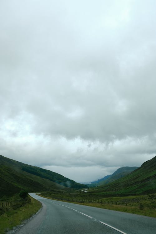 Foto d'estoc gratuïta de carretera buida, cel ennuvolat, muntanyes verdes