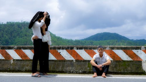 Young Couple Hugging and a Man Sitting Alone next to Them 