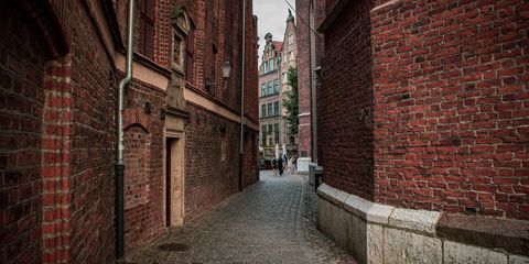 Explore a quaint cobblestone alleyway surrounded by historic brick buildings on a quiet day.