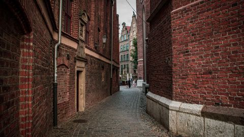 Explore a quaint cobblestone alleyway surrounded by historic brick buildings on a quiet day.