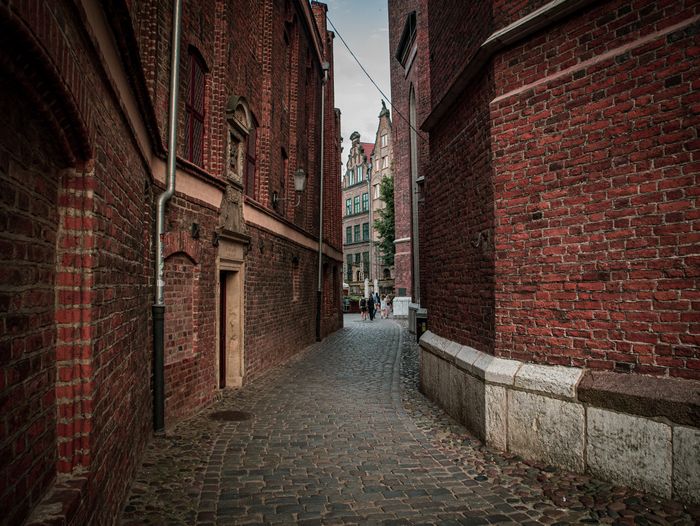 Narrow cobbled lane between brick walls, photo by Aliaksei Semirski on Pexels