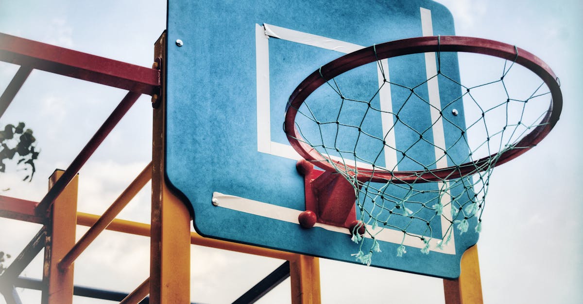 Close-up of an outdoor basketball hoop against a bright blue sky, highlighting sports equipment.