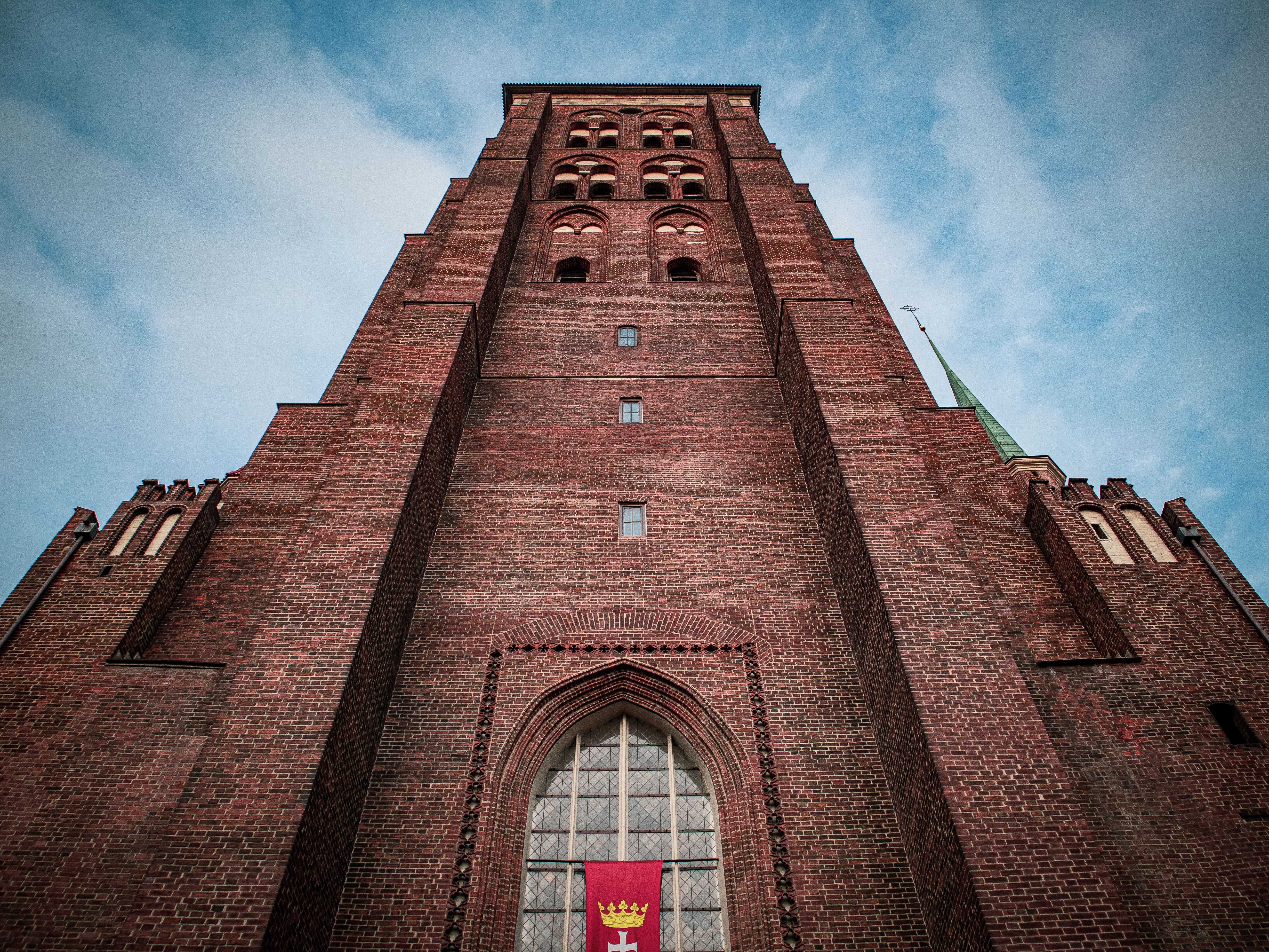 Gothic-style church tower in Gdańsk, highlighting its classic brick construction against a blue sky.