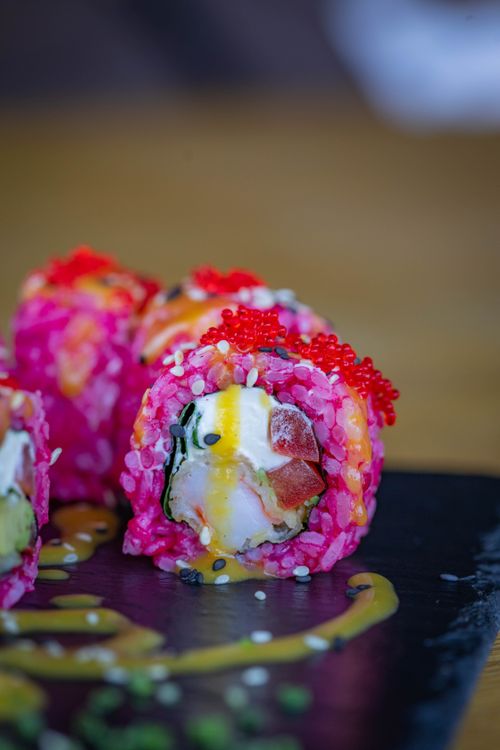 Free Colorful sushi roll with toppings on a slate plate. Perfect for food lovers. Stock Photo