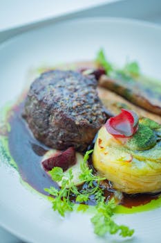 Close-up of a gourmet beef steak with sauce and herbs, artfully plated.