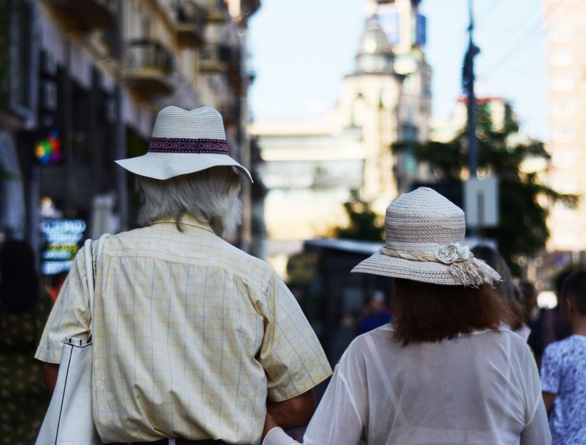 Un momento sereno capturado de una pareja de ancianos caminando por una calle bulliciosa de la ciudad, mostrando conexión.