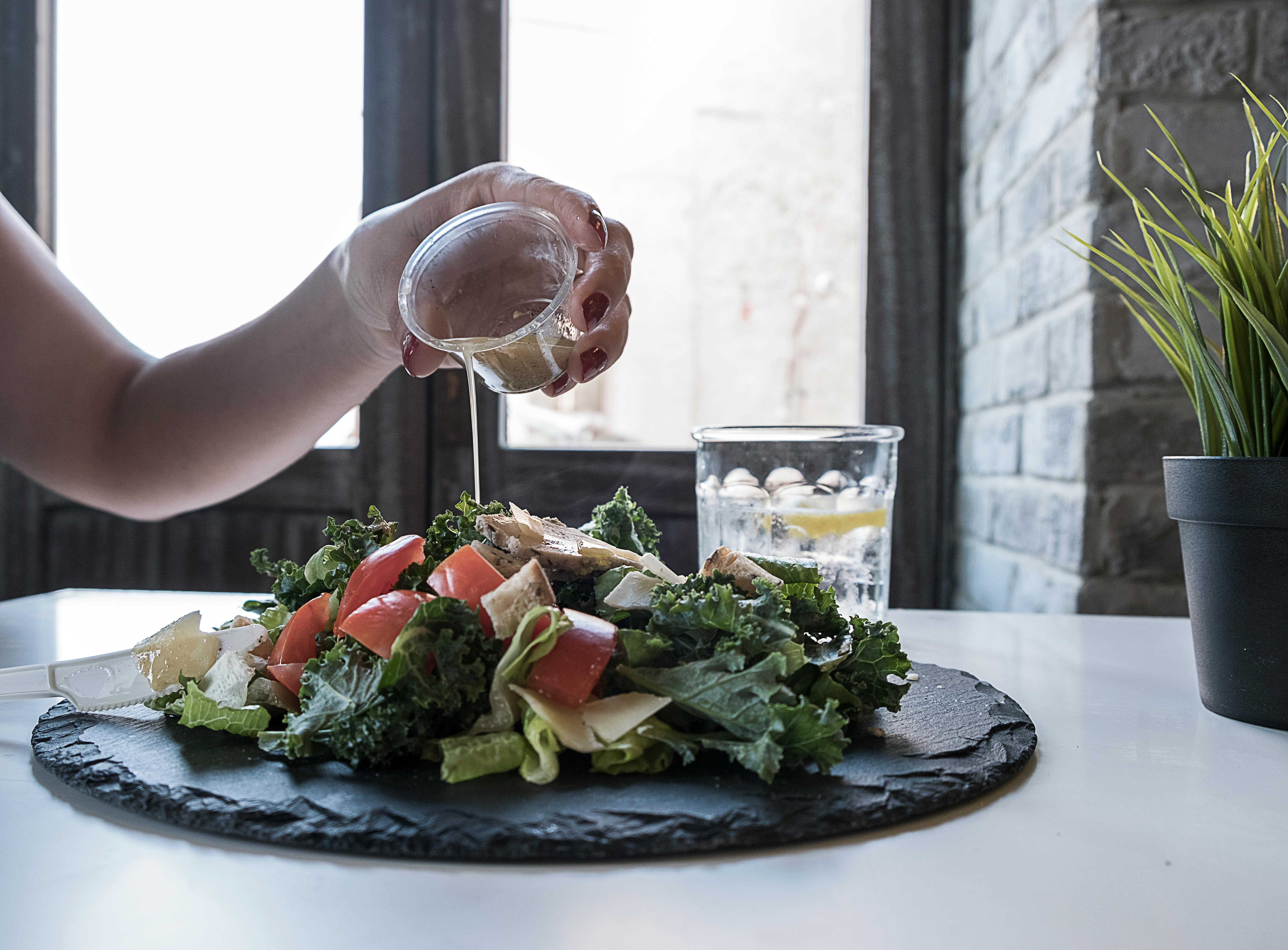 Person pouring dip on vegetable salad. | Photo: Pexels