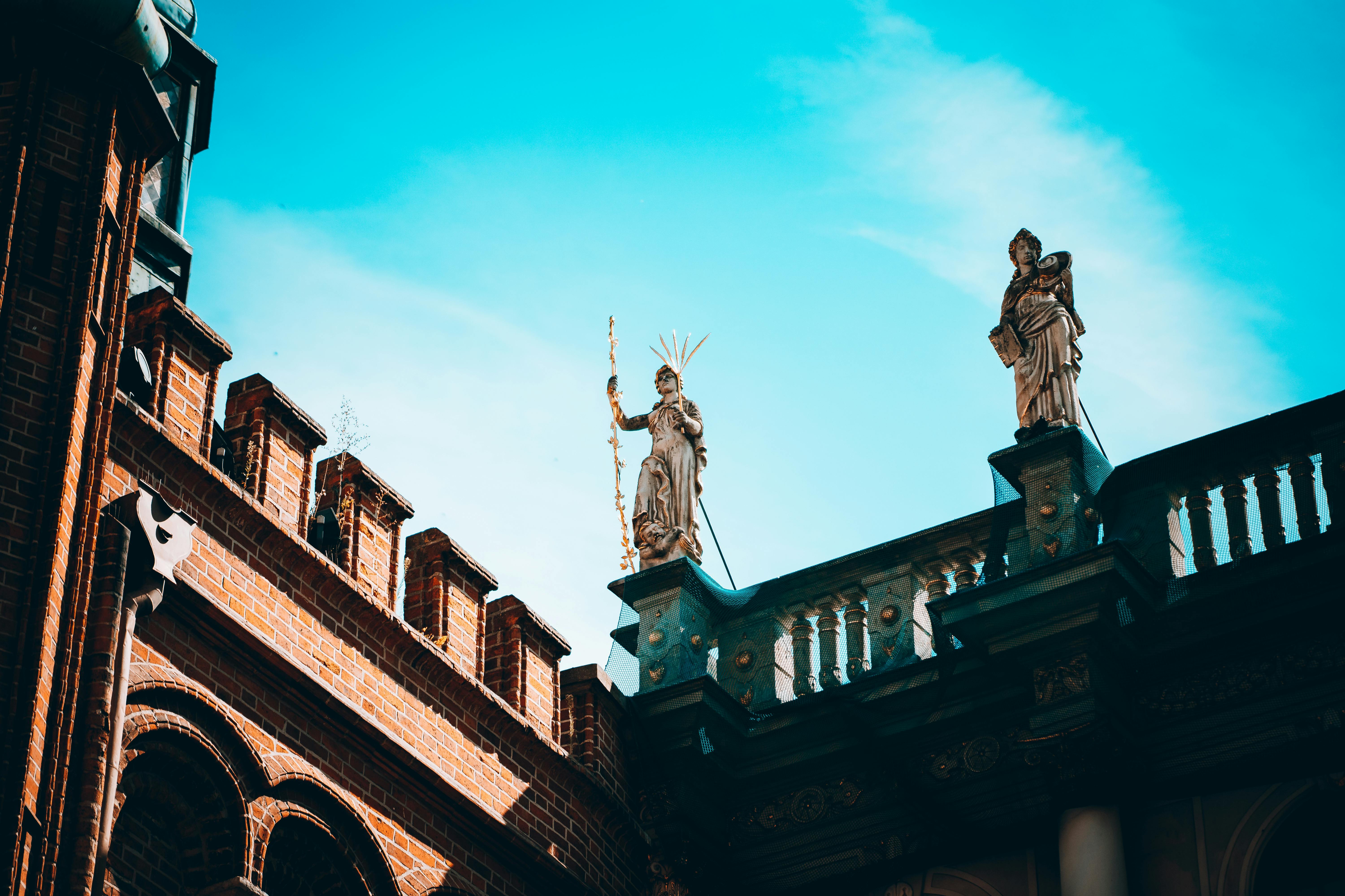 A Pair of Statues on Top of Building under Blues Sky · Free Stock Photo