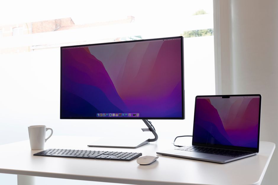 Sleek home office setup with a monitor, laptop, keyboard, and mouse on a minimalist desk.