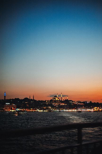 Breathtaking view of Istanbul's skyline with illuminated mosques at sunset from the Bosphorus Strait.