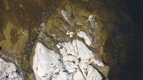 Free Aerial shot of rugged rock formations along the coastline of Västernorrlands län, Sweden. Stock Photo