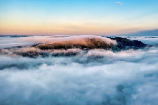 A breathtaking aerial view of a fog-covered mountain peak at sunrise in Weaver, Minnesota.