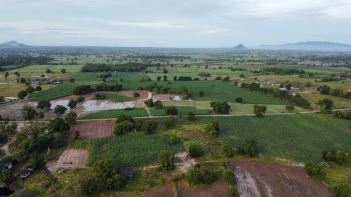 Free Aerial image showcasing lush green fields and distant mountains under a cloudy sky. Stock Photo