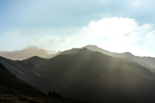 A captivating view of sunlit mountain peaks and clouds casting a serene ambiance.
