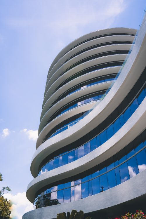 Free Architectural modernity reflected in curved glass with blue sky backdrop. Stock Photo