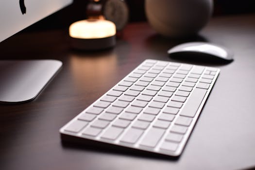 A minimalist workspace featuring a wireless keyboard, mouse, and desktop on a wooden table.