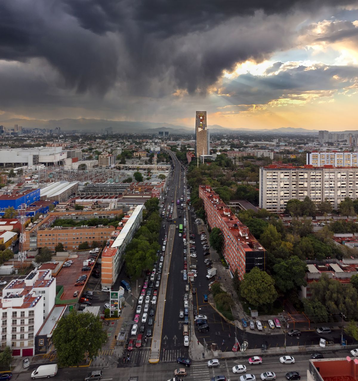 Aerial view of Mexico City's skyline under dramatic stormy skies during sunset.