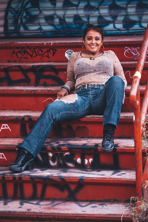 Woman in Blue Denim Jeans Sitting on a Staircase