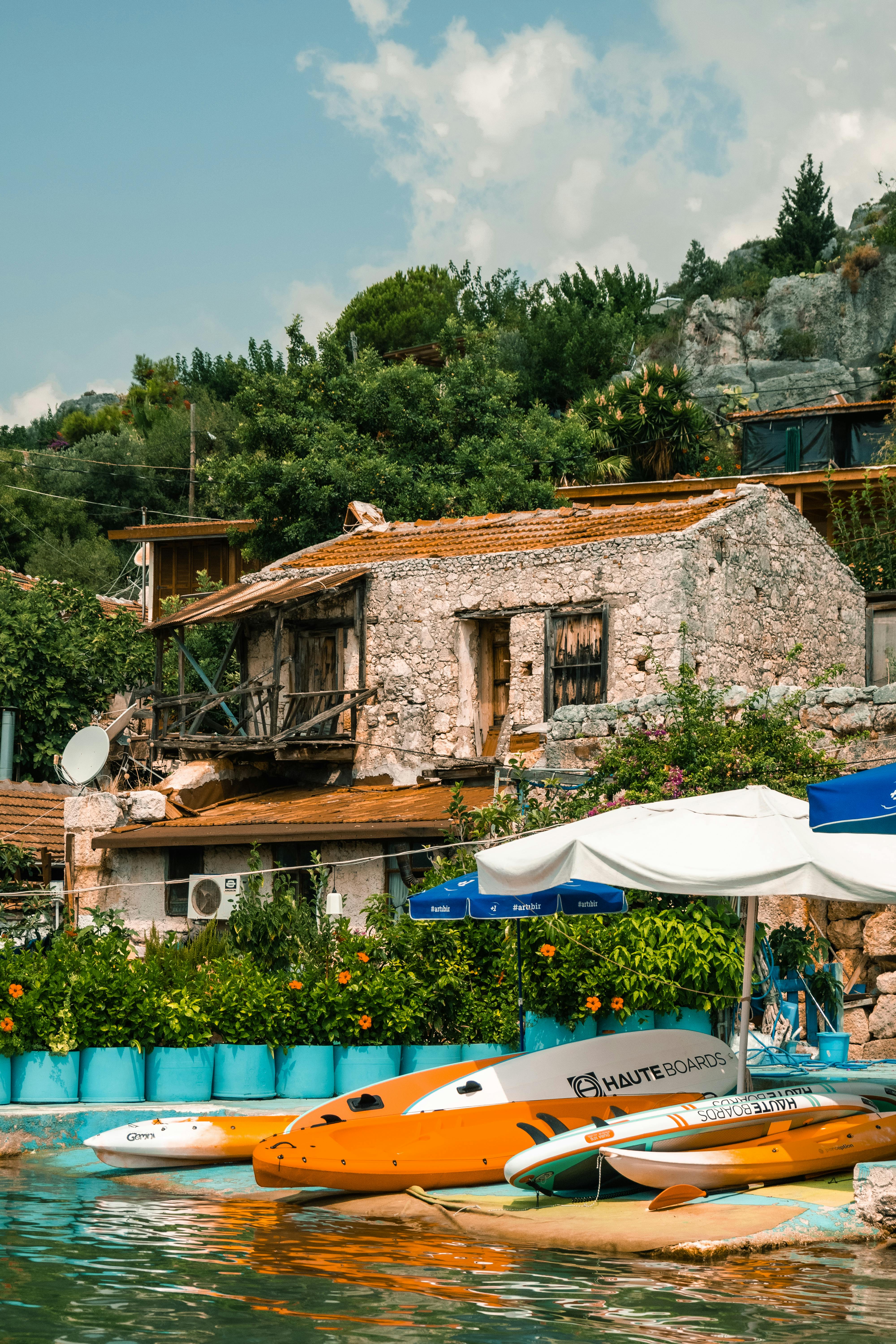 Kayaks Under a Beach Umbrella Near a Body of Water · Free Stock Photo