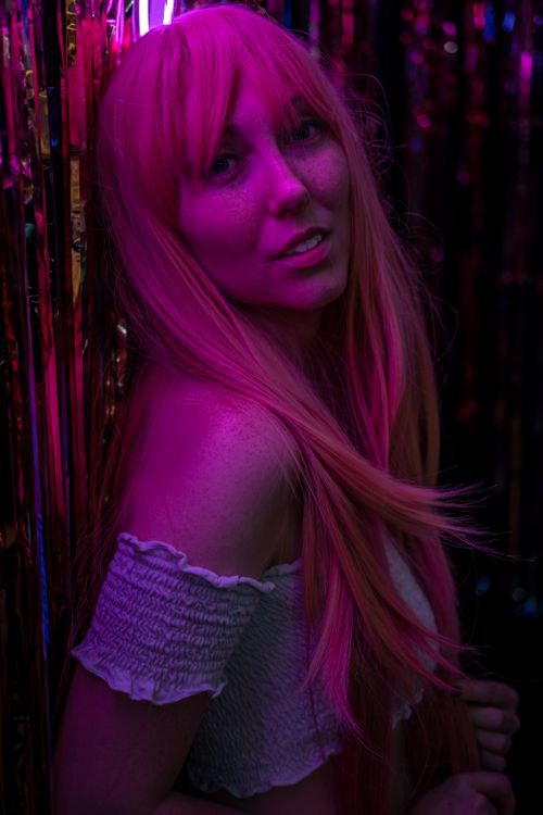 Free Stunning portrait of a young woman with neon pink lighting effect, exuding a modern and stylish vibe. Stock Photo