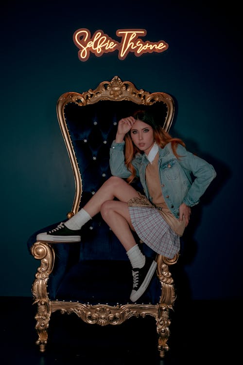 A Woman Sitting on Blue and Gold Armchair