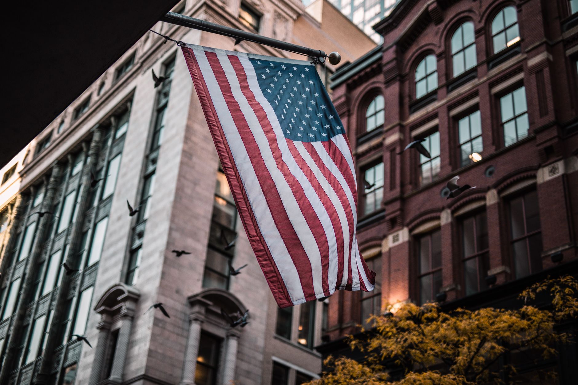 Low angle shot of American flag waving amidst historic city buildings.