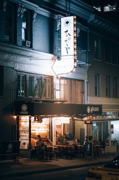 Lively urban cafe scene at night in San Francisco with outdoor seating and glowing signage.