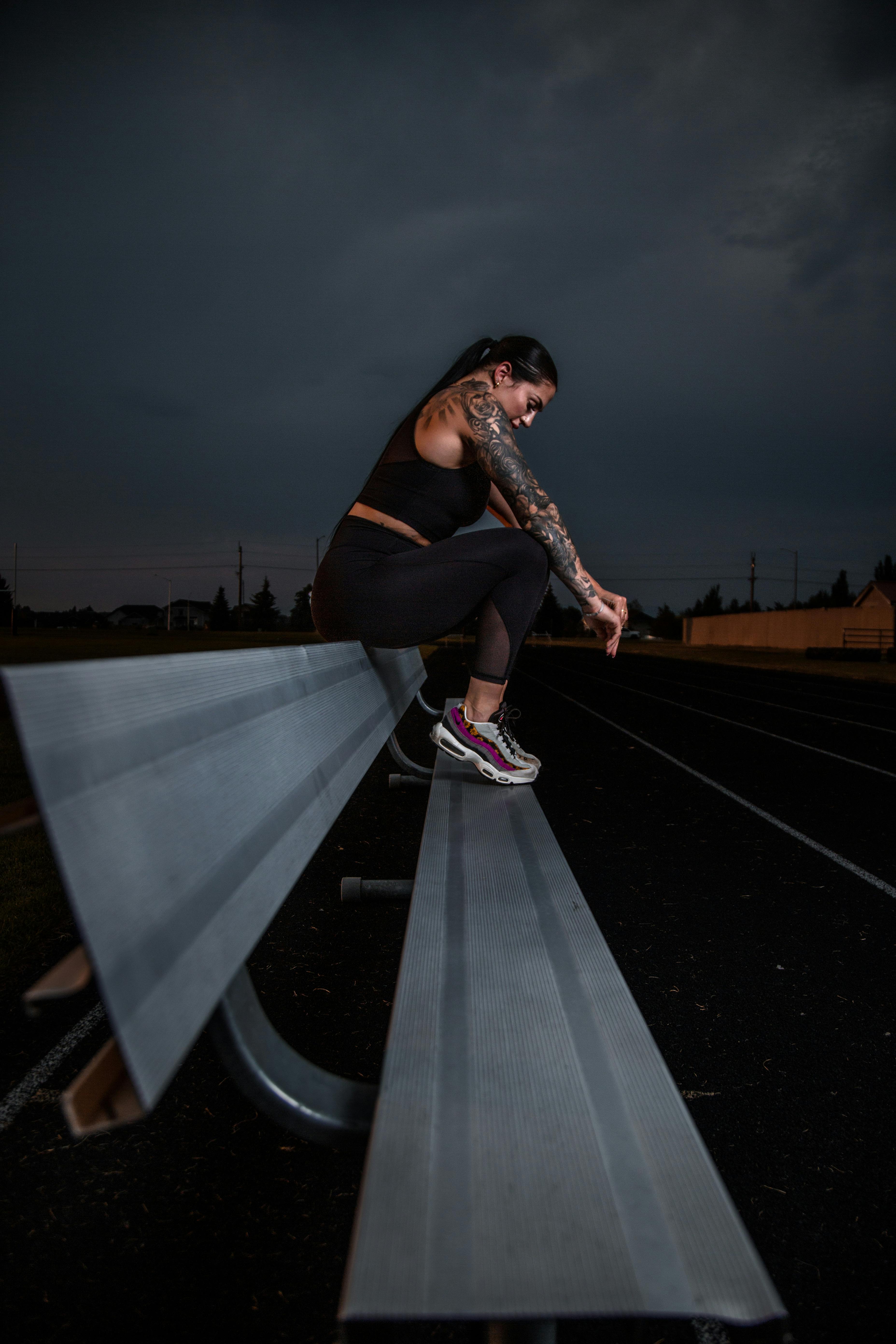 Free Woman with Tattoos in Sportswear Sitting on Bench Stock Photo