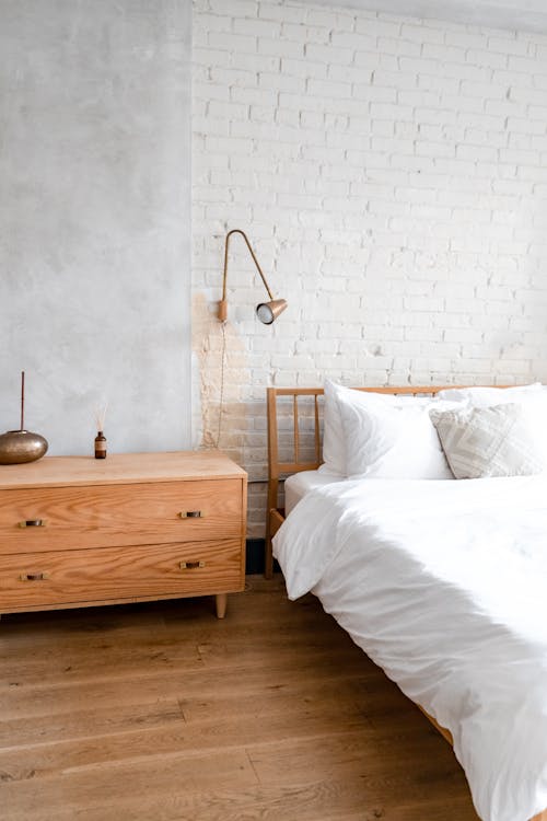 Free Brown Wooden Bed Frame With White Bed Linen Stock Photo