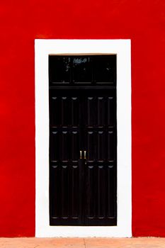 Elegant black wooden door set against a vibrant red wall with white trim. Urban minimalism at its best.