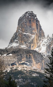 Breathtaking view of a majestic alpine peak with a rugged cabin nestled below, evoking adventure.
